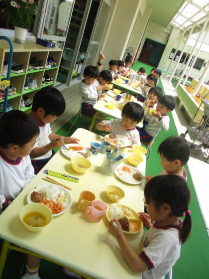 給食も始まっています。この写真は天気の良い日の一コマです。風の心地よさをかんじたり、小鳥の鳴き声を聞きながらの給食はいつもと違って子どもたちの食欲がとまりませんでした。こんな日もいいですね。